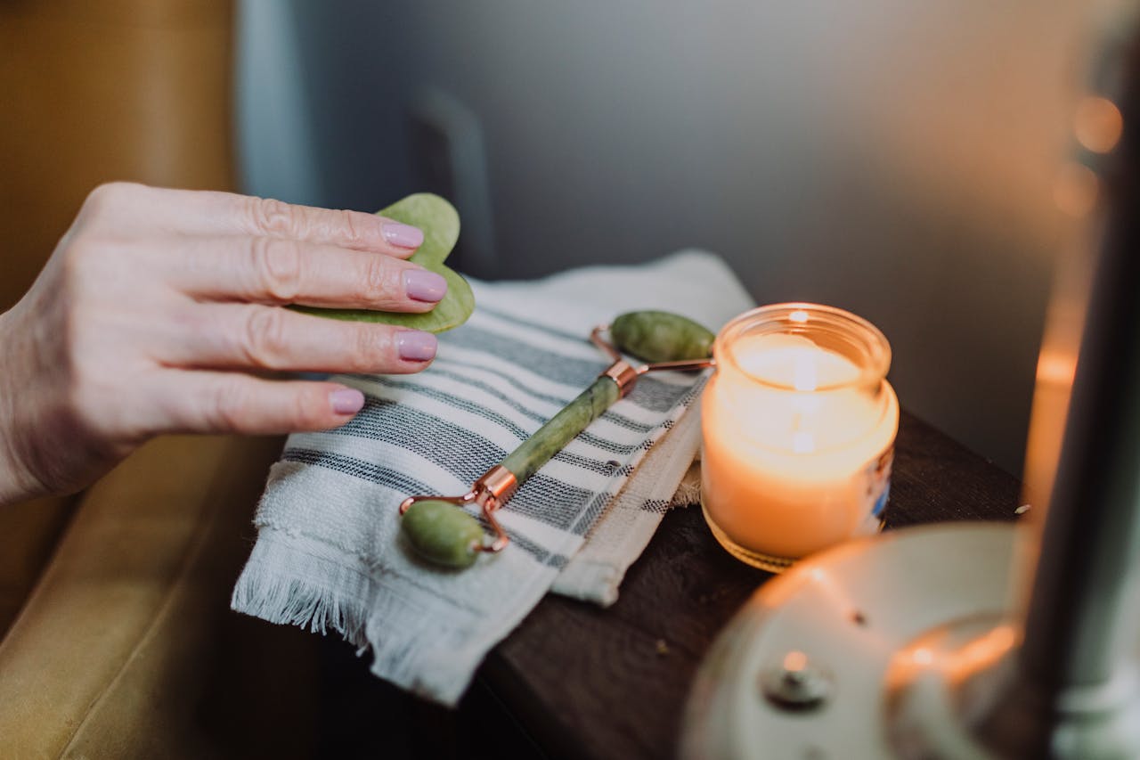 A calming self-care setup featuring a jade roller, candle, and cozy ambiance, perfect for relaxation.